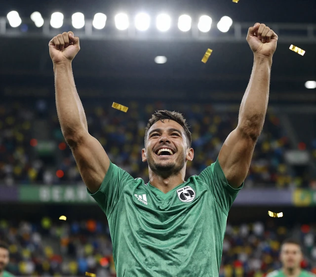 Golazzo Model im Fu&szlig;balltrikot jubelt mit erhobenen Armen &uuml;ber einen Wettgewinn im Konfettiregen unter Flutlicht